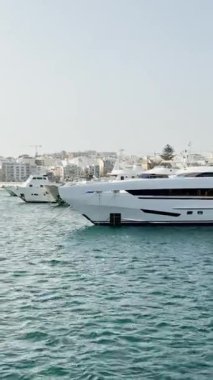 Malta, Valletta - 23 Mart 2025: Limanın güzel manzarası ve körfezdeki büyük yatlar, eski kasaba mimarisi ve yat limanı, manzara, körfez manzaralı dikey video.
