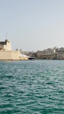 Malta, Valletta - 23 Mart 2025: Güney Avrupa, eski kent yakınlarındaki büyük yatın güzel manzarası, mimarlık ve yat limanı, dikey video manzarası, körfez manzarası.