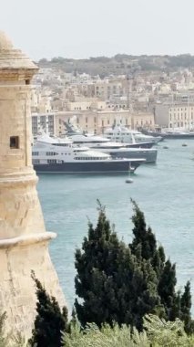 Malta, Valletta - 23 Mart 2025: Bay, eski kent, mimarlık ve yat limanı yakınlarındaki büyük yatların manzarası, dikey video manzarası.