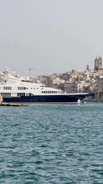 Malta, Valletta - 23 Mart 2025: Güney Avrupa, limanın güzel manzarası ve körfezdeki büyük yatlar, eski kasaba ve yat limanı, körfez manzaralı dikey video.