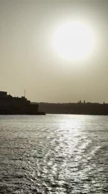 Günbatımı körfez manzarası, ufukta eski kasaba mimarisi, günbatımı video manzarası, gün batımında deniz manzarası..