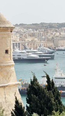 Malta, Valletta - 23 Mart 2025: Eski kentin yakınındaki büyük yat ve geminin güzel körfez manzarası, mimari ve yat limanı, dikey video manzarası.
