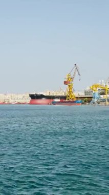 Malta, Valletta - 23 Mart 2025: Liman manzarası ve eski kasabanın körfezindeki büyük gemiler, mimari ve yat limanı, dikey video manzarası.