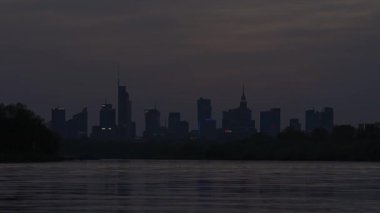 Varşova, Polonya - 17 Nisan 2025: Şehir manzarası, ufukta gökdelenlerin siluetleri, göl ve şehir merkezi, gece vakti iş merkezi.