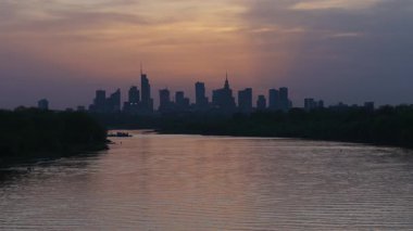Varşova, Polonya - 17 Nisan 2025: Günbatımı şehir manzarası, ufukta gökdelenler, şehir nehri ve şehir merkezi manzarası, akşam iş merkezi.