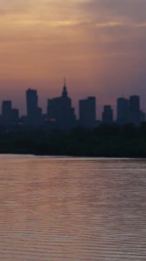 Bulanık manzara, gün batımı akşam manzarası, ufuktaki gökdelenlerin dikey videosu, şehir nehri ve şehir merkezi, gece vakti iş merkezi, alan derinliği..