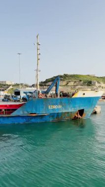 Malta, Valletta - 23 Mart 2025: Deniz işleri, körfezdeki liman ve kargo teknik gemisinin deniz manzarası, yat limanı, dikey video manzarası.