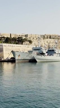 Malta, Valletta - 23 Mart 2025: Eski kasabanın körfezindeki liman ve eski Sahil Güvenlik gemileri, mimari ve yat limanı, dikey video manzarası.