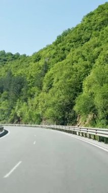 Birinci şahıs manzarası, yeşil tepelerden geçen yaz yolu, Avrupa 'ya yolculuk, otobanda hareket halindeki bir arabadan manzara, doğal manzara..