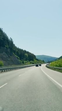 Güneşli bir günde otoban, hareket halindeki bir arabadan birinci şahıs manzarası, yaz doğal manzarası, tepe arazisi, yolda giden arabalar..