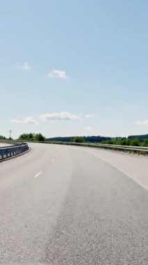 Otobandaki hareketli bir arabadan birinci şahıs görüntüsü, yazın erken saatlerinde doğal manzara, tepe arazisi, boş yolda araba yolculuğu..