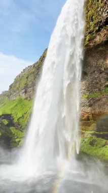 İzlanda şelale manzarasının güzel manzarası, İzlanda doğası ve dünya dokusunun huzur manzarası, su ve gökkuşağının akışı, yeşil kayalık arazi arka planı.