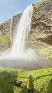 Yeşil kayalık arazi, İzlanda şelalesinin güzel manzarası, İzlanda doğası ve dünya dokusunun huzur manzarası, su ve gökkuşağının akışı, yeşil kayalık arazi arka planı...