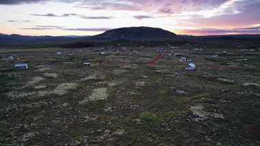 İzlanda manzaralı, dağ vadisine karşı küçük otel evleri manzaralı, volkanik bir vadinin günbatımı manzaralı, misafirler için evler ve turizm altyapısı, toprak dokusu, doğa arka planı.