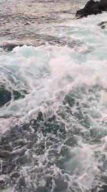 Gün batımında sakin doğa manzarası, deniz manzarası, dalgalar ve kayalar, sabit dikey arka plan, kayalara çarpan dalgalar, su dokusu.