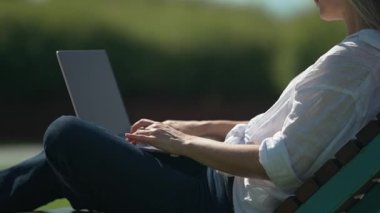 El bilgisayarı, beyaz tişört giyen, laptopla çalışan, bilgisayar başında çalışan, yetişkin öğrenci daktilo metni kullanan, güneşli hava koşulları olan bir kadın..