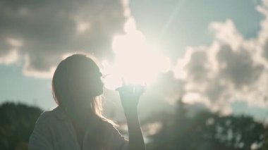 Şişeden su içen kadın, doğada otururken, sağlık ve su dengesi, akşam vakti, yavaş çekim.