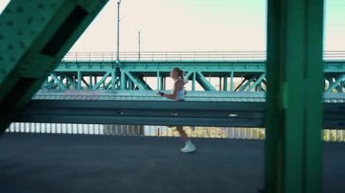 Varşova, Polonya - 20 Eylül 2025: Sabah koşusu, nehrin üzerindeki köprüde koşan güzel bir kadın, yarı maraton antrenmanında profesyonel koşucu.