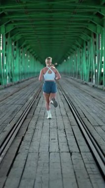 Varşova, Polonya - 20 Eylül 2025: Sabah koşusu, nehrin üzerindeki köprüde koşan güzel bir kadın, kardiyo eğitimi, maraton hazırlığı.