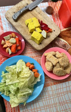 Buharlı gemi, tofu, chili, sebze, havuç, nugget ve biber tozundan oluşan hazır yemek malzemeleri ve bir bıçak.