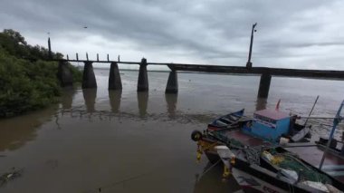 Denizde birkaç balıkçı teknesi rıhtım köprüsünün yanında, huzurlu bir deniz manzarasını vurguluyor.
