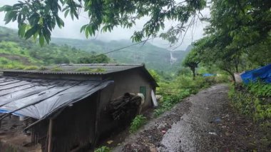 Muson sırasında Maharashtra 'nın sakin kırsal bir köyünde, yemyeşil ve doğa ile çevrili geleneksel kulübeler var..