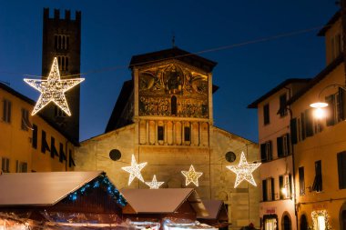  Lucca, İtalya, 17 Aralık 2022 - Lucca 'da Noel. St. Frediano Ortaçağ Kilisesi önünde yıldızlı Noel pazarı