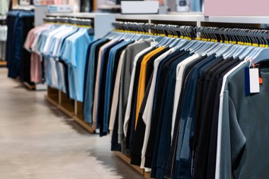 Bir mağazada askıda asılı bir sıra kıyafet. Alışveriş merkezinde elbise askıları..