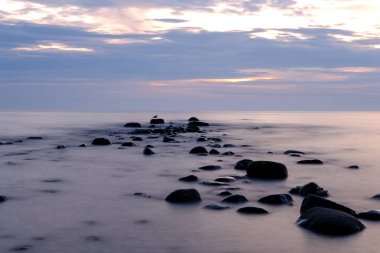 Göldeki taşlı plajın üzerinde gün batımı. Taşın üzerinde martı var. Elgin Gölü kıyısında. Huron Gölü.