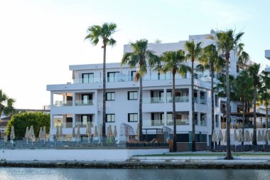 Palmiyeleri ve havuzu olan tipik bir otel binası.