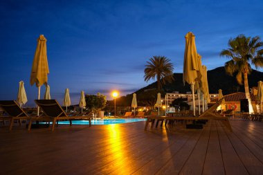 Tipik bir otelde gün batımından sonra havuz.