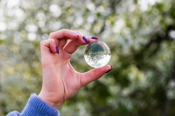 stock image A hand holds a glass layer. Which turns the world upside down. How light reflect on crystal ball.