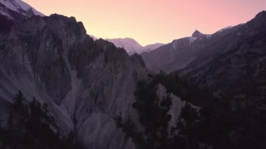 Flying over jagged terrain through canyon in Manang Nepal at dusk.