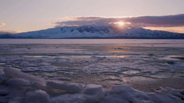 夕阳西下 犹他冰封的湖面上 随着云彩在冬季地平线上翻过高山 时间消逝了 — 图库视频影像