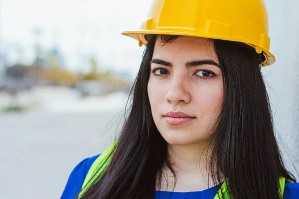 portrait of young caucasian female engineer wearing protective helmet and safety vest, smiling looking at camera, engineering concept, copy space.