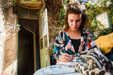 Fransız kökenli beyaz bir kadının portresi, terasında oturuyor, çizim yapıyor, yaşam tarzı kavramı üzerinde çalışıyor, kopyalama alanı kullanıyor..