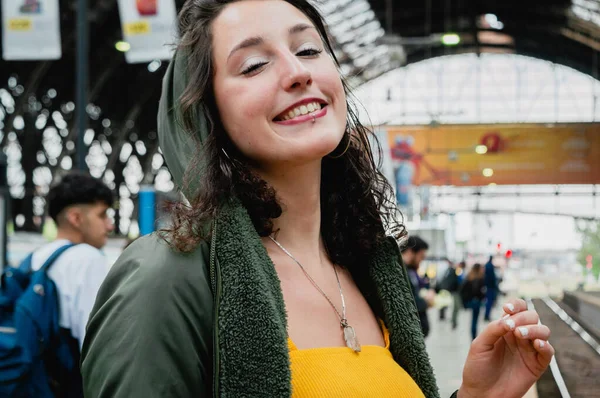 Portrait of a young Latina woman with white skin, dressed in yellow, looking at the camera, she is very happy because she is going on a train trip to the province of Buenos Aires.