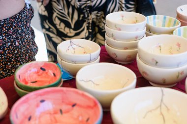 Farklı renkte seramik kaseler üst üste yığılmış, bir sanat fuarında sergileniyor..