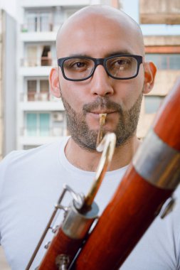 Sakallı, gözlüklü, basson çalan ve kameraya bakan Latin bir adamın yakın plan portresi. Müzik konsepti..