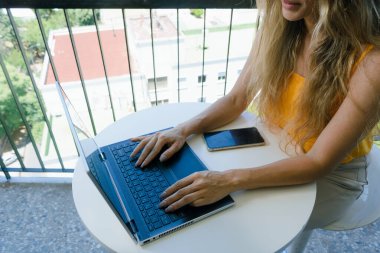 Balkonda oturan tanınmayan genç bir kadının üst görüntüsü dizüstü bilgisayarı, teknoloji konsepti, kopyalama alanı..