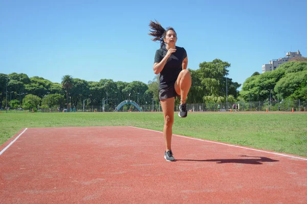 年轻的拉丁裔女子 带着弯曲的腿跳 运动理念 复制空间 在跑道上热身 — 图库照片