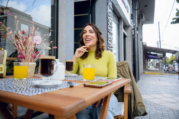 stock image young argentinian latin woman, she is laughing chatting with her friend while having breakfast outside the cafeteria, drinking coffee, lifestyle concept, copy space.