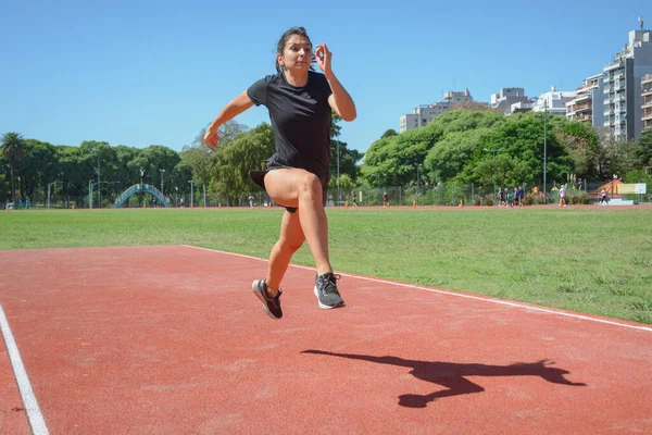 穿着黑色运动服的年轻的阿根丁拉丁女赛跑选手 训练在跑道上跳远 运动理念 复制空间 — 图库照片