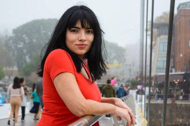 Genç Latin Venezuelalı turist, Buenos Aires 'te yürüyüş yapmak için, Puente De La Mujer' de, bulutlu bir günde, dinlenen kameraya sakince bakıyor..