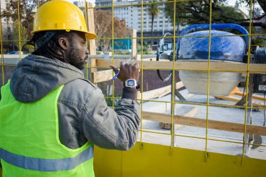 Sarı kasklı genç bir inşaat mühendisi, güvenlik bariyerinin önünde duruyor inşaat işçileri, inşaat konsepti, kopyalama alanı denetliyor..