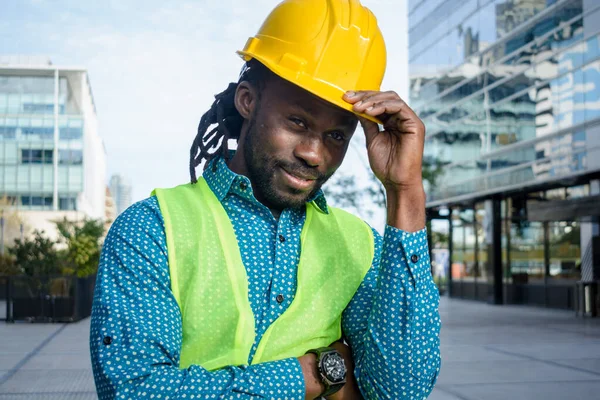 Siyah Adam Mühendis Açık Havada Duruyor Tek Eliyle Şapkasını Tutuyor — Stok fotoğraf