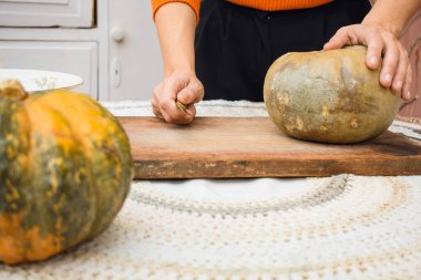 Elinde bıçak ve balkabağı olan, daha fazla çiğ balkabağı, vegan ve vejetaryen tarifleri hazırlayan beyaz bir kadının ön görüntüsü. Boşluğu kopyala