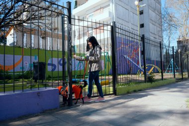 Siyah saçlı ve soğuk algınlığı için ceket giyen genç Latin Venezuelalı kadın gün batımında kapısının açılmasından mutlu. Siyah melez köpeğiyle parka giriyor. Oyun, yaşam tarzı konsepti, kopyalama alanı.