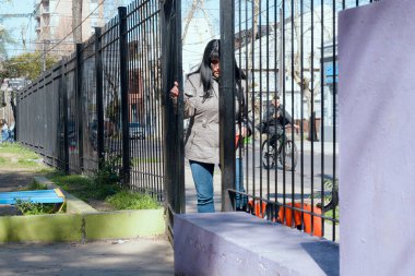 Soğuk hava ceketi ve kot pantolon giyen uzun siyah saçlı mutlu Latin kadın öğleden sonra gelip evcil hayvanıyla oynamak için parka giriyor..