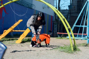 Güneşli bir günde parkta mutlu genç bir Latin kadın köpeğini oyun oynaması için serbest bırakıyor, evcil hayvanlar ve yaşam tarzı konsepti, kopyalama alanı.
